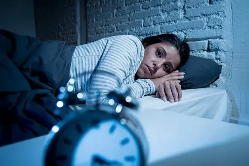 Lady awake in bed, as could happen due to sleep problems from methadone.