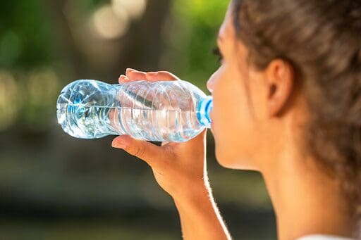 Woman drinking water, keeping hydrated as part of exercise and nutrition for addiction recovery.